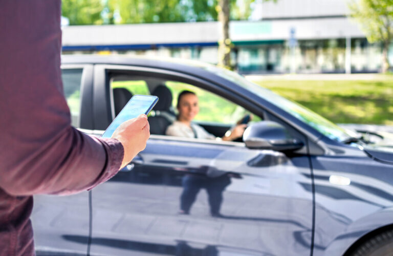 a person holding a phone in front of a car